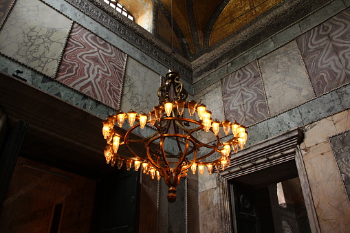 Istanbul, Turkey-May 11, 2014: Architectural Sections from the Interior of the Hagia Sophia Mosque, Columns, arches and dome decorations. Decorations on the yellow ceiling. The walls are covered with marble. There is a big chandelier on the ceiling.