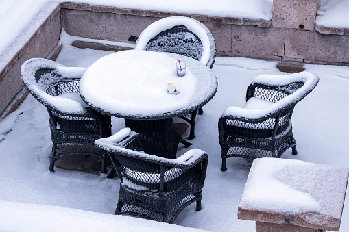 Table, empty chairs, empty juice glass and empty coffee cup under the snow at Cappadocia