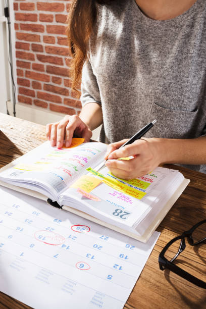 Businesswoman Making Schedule On Personal Organizer Close-up Of A Businesswoman Making Agenda On Personal Organizer At Workplace 21 24 months stock pictures, royalty-free photos & images