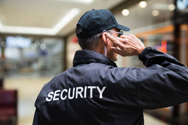 istock Security Guard Listening To Earpiece Against Building 1303166948
