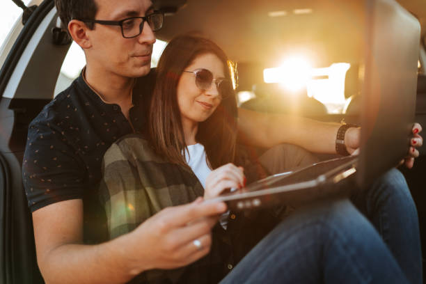 istock Young couple using laptop in open car trunk 1303167907