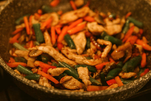 Fried vegetables with turkey meat in a black iron wok pan