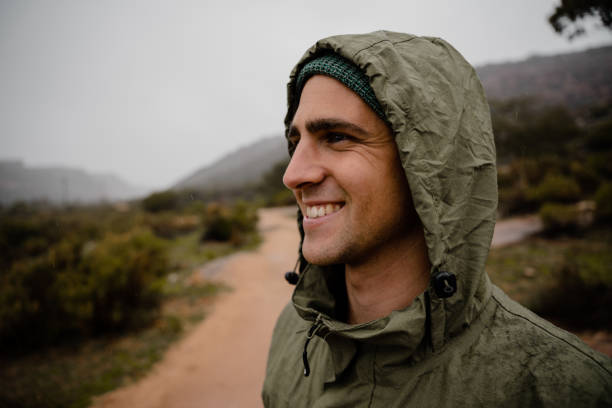 istock Smiling handsome young male athlete happy with views on mountain path wearing rain jacket for projection from weather 1303170428