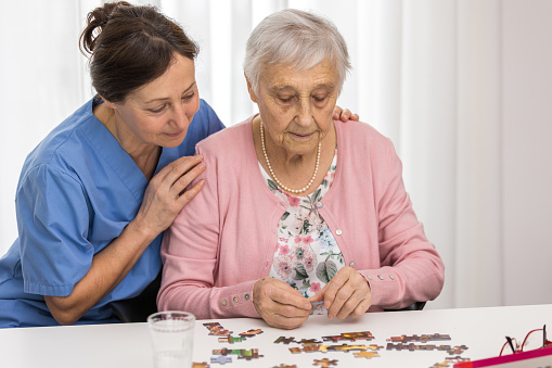 Therapy - Senior woman playing jigsaw puzzle in nursing home