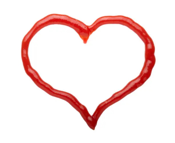 Photo of The heart is made of red tomato sauce or ketchup isolated on white background