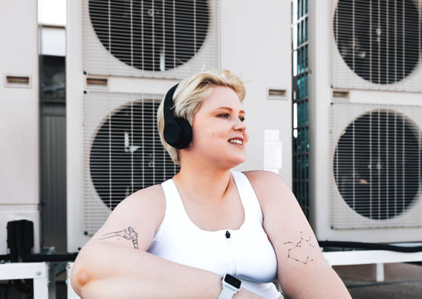 Smiling curvy woman in sportswear sitting on the roof at air conditioning units Smiling curvy woman in sportswear sitting on the roof train air conditioner stock pictures, royalty-free photos & images