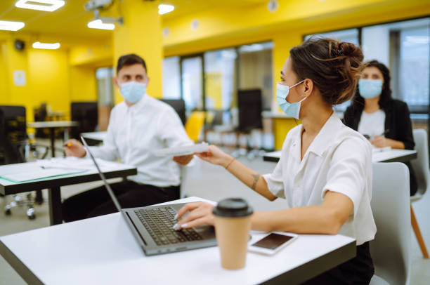 istock Young people with face masks back at work or school in office after lockdown. 1303180252
