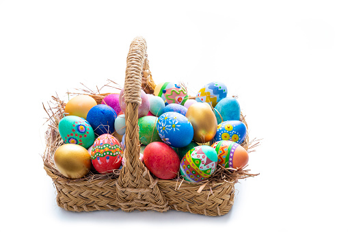 Easter eggs hand painted in a straw basket isolated on white background