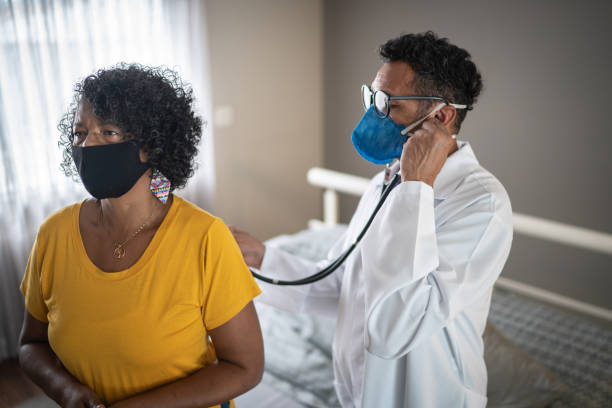 Doctor listening to patient's heartbeat - wearing face mask
