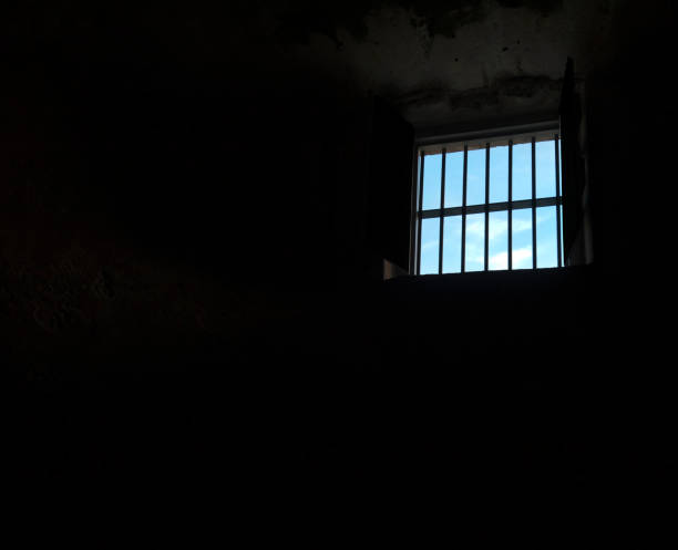 istock dark room, jail cell window showing sunny day outside 1303185385