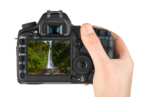 Hand with camera and Gitgit Waterfall in Bali Indonesia (my photo) isolated on white background