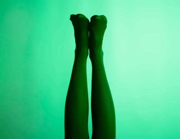 slim female legs in tights raised up over green background - witchcraft heights imagens e fotografias de stock