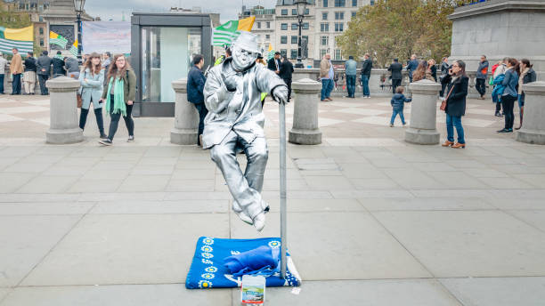 An unidentified busking mime performs on Trafalgar Square. Street performer spray painted silver is the entertainment for the tourist