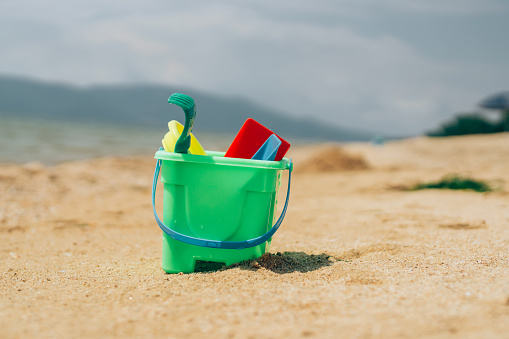 Beach toys in sand on the beach by the sea.