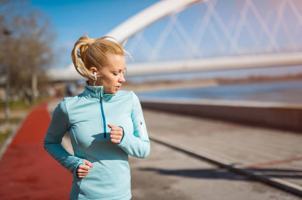 Mid adult woman having a morning jog on a mid cold day next to river.