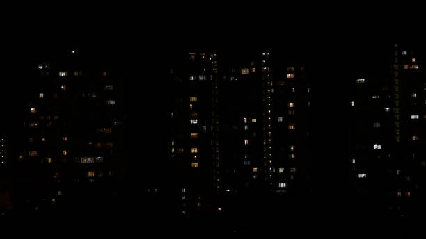 istock Night lights in windows of multistory buildings in darkness 1303197542