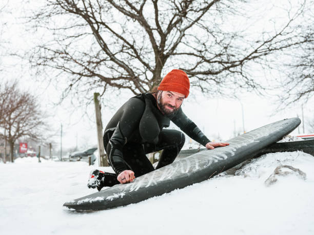 istock Young man getting ready to surf in winter 1303198524