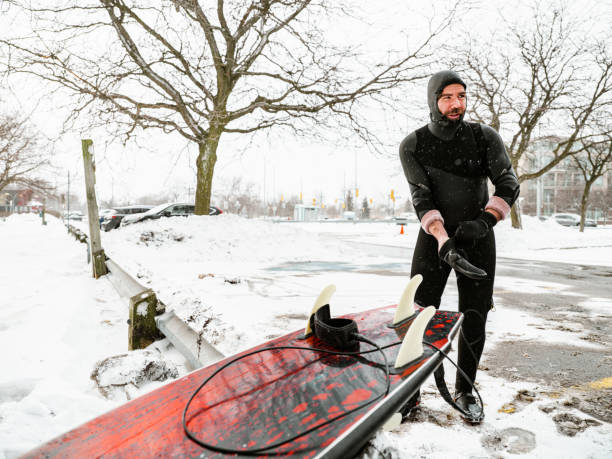 istock Young man getting ready to surf in winter 1303198673