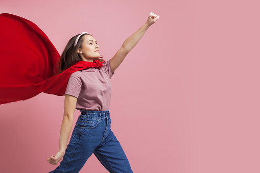 Superheroine, a young female superhero in a red Cape hurries forward