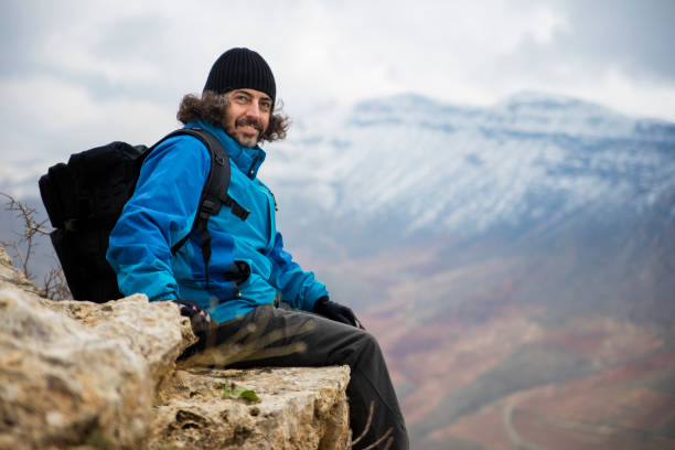 Male mountaineer sitting on the top o cliff