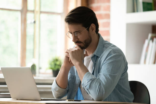 istock Pensive male employee work on laptop in office thinking 1303206538