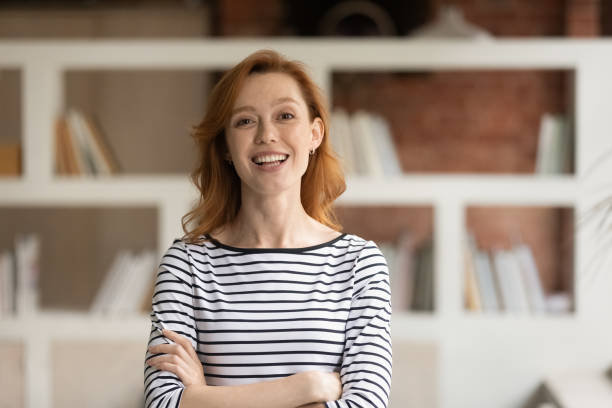 Portrait of smiling Caucasian businesswoman pose in office Portrait of smiling young Caucasian businesswoman pose in modern office. Happy 30s red-haired European female employee or worker show leadership and success at workplace. Recruitment concept. real estate agent photos stock pictures, royalty-free photos & images