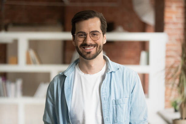 Portrait of smiling Caucasian man pose in office Portrait of smiling millennial Caucasian male tutor or coach wear glasses pose in modern office of classroom. Headshot of happy young man employee satisfied with work job. Employment concept. salesman photos stock pictures, royalty-free photos & images
