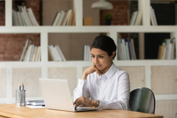 istock Pensive Indian woman work on laptop thinking 1303206663