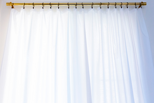 White curtain with golden rod hanging in the window, background with copy space, full frame horizontal composition