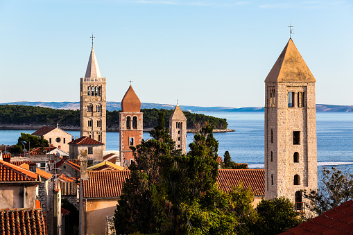 The City of Rabs Church Towers and Houses Overlooking the Sea and a Green Forest