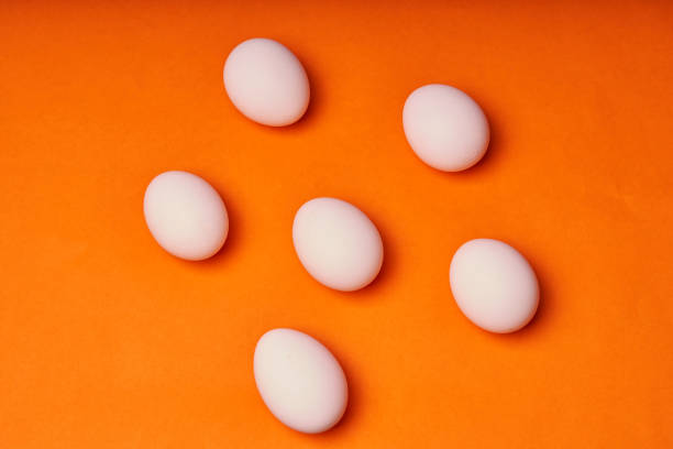 istock Chicken eggs laid out on an orange background 1303207966