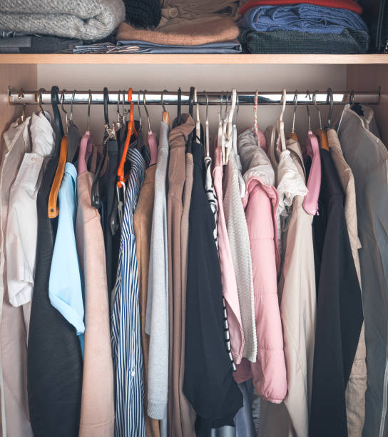 Women's clothing hangs on hangers in the closet Women's clothing hangs on hangers in the closet. Wardrobe with different clothes, household items, a selection of clothes in the closet. colorful check shirts on sale at a clothing store stock pictures, royalty-free photos & images
