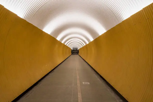 Photo of Perspective view of long modern futuristic yellow underground pedestrian tunnel in Stockholm Sweden.