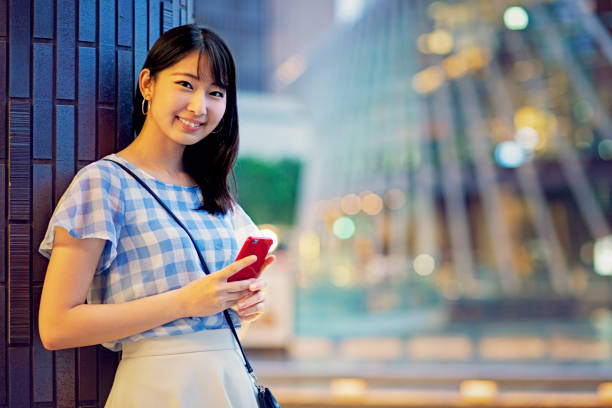 携帯電話を使った日本の若い女性の肖像 - 待つ ストックフォトと画像