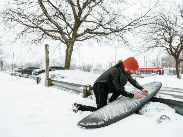 istock Young man getting ready to surf in winter 1303214907