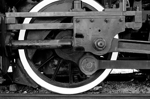 close view of train wheel and other parts of train, no people, antique steam engine, sunny day