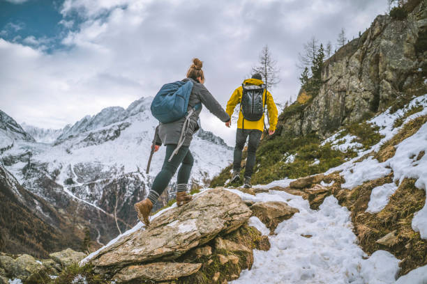 ハイカーの若いカップルが一緒に尾根を縛った - snow hiking ストックフォトと画像