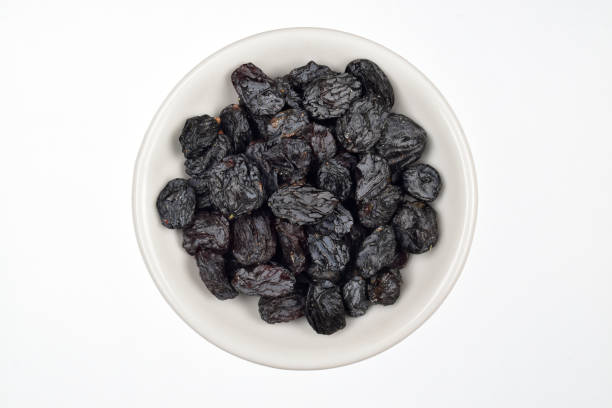 istock Dried plum in bowl isolated on white background with clipping path 1303216884