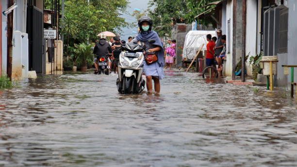 residenti mentre passano attraverso un'acqua alluvionale - floodwaters foto e immagini stock