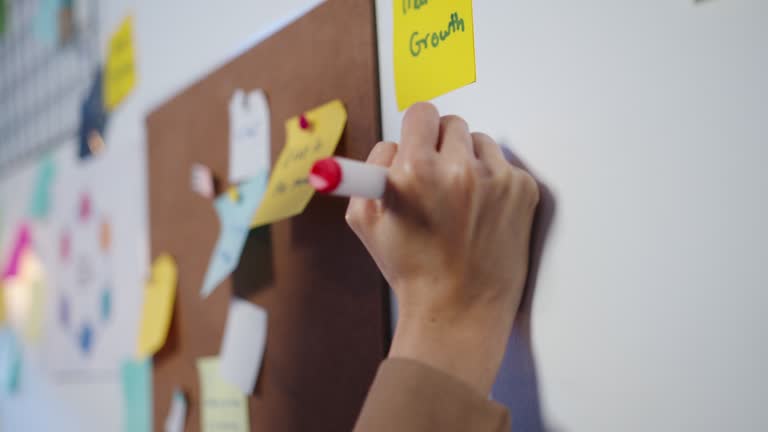 Group of young Asia businesspeople discussing business brainstorming meeting working together sharing data and writing whiteboard on wall with sticky note in night office.