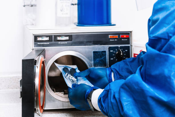 istock unrecognizable person in bio security suit holding tools and putting them into a machine to sterilize them. 1303223710