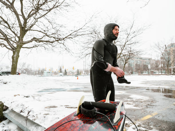 istock Young man getting ready to surf in winter 1303223718