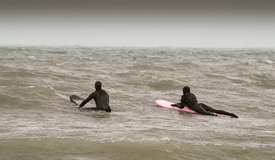 Canadian style surfing: Young couple on the waves ready to surf at the lake. Surfing in extreme weather conditions.