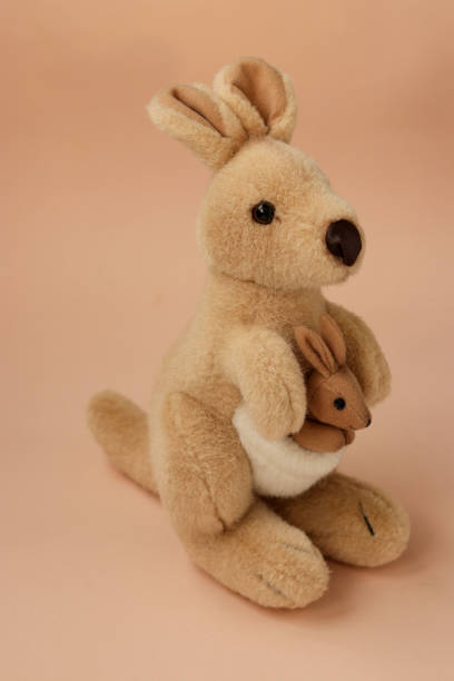 istock Soft toy mom kangaroo with a baby is located on a peach background, vertical 1303224507
