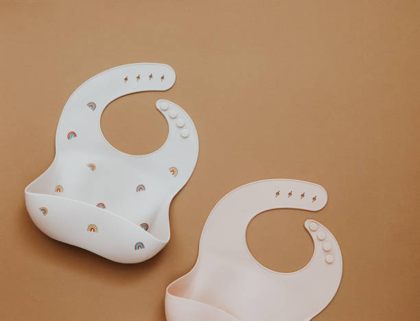 istock Cute baby bib for food on brown light background, top view, copy space 1303224839