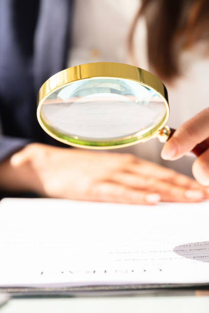 istock Businesswoman Looking At Contract Form Through Magnifying Glass 1303227793