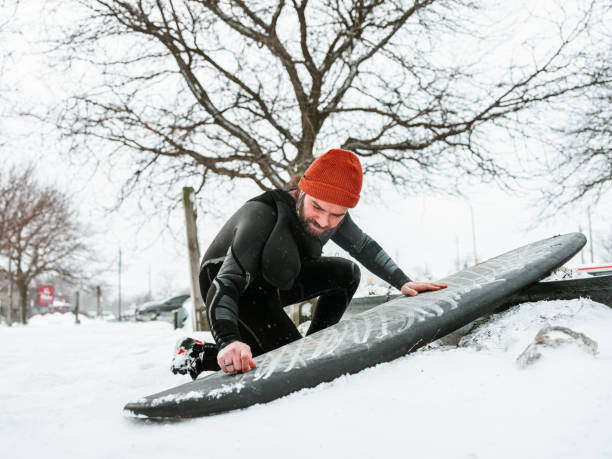 istock Young man getting ready to surf in winter 1303228777