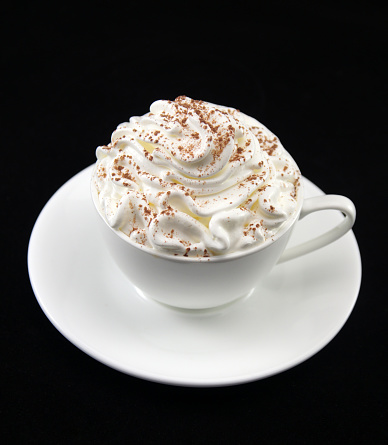 Einspanner Viennese Coffee (espresso with whipped cream and chocolate) in a white cup isolated on a black background.
