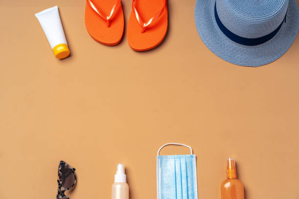 istock Top view of beach accessories and protective mask on beige background 1303234780