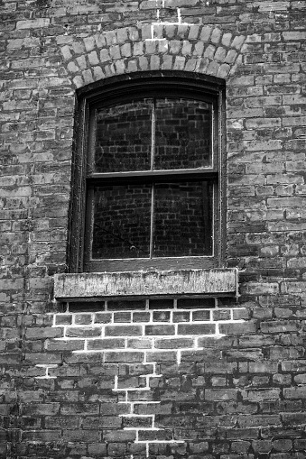Old window panes in red brick walls with some masonry works done on them in an old industrial area of Toronto now turned to a bar, cafe and restaurant neighborhood called Distillery Neighborhood which is a Tourist attraction.